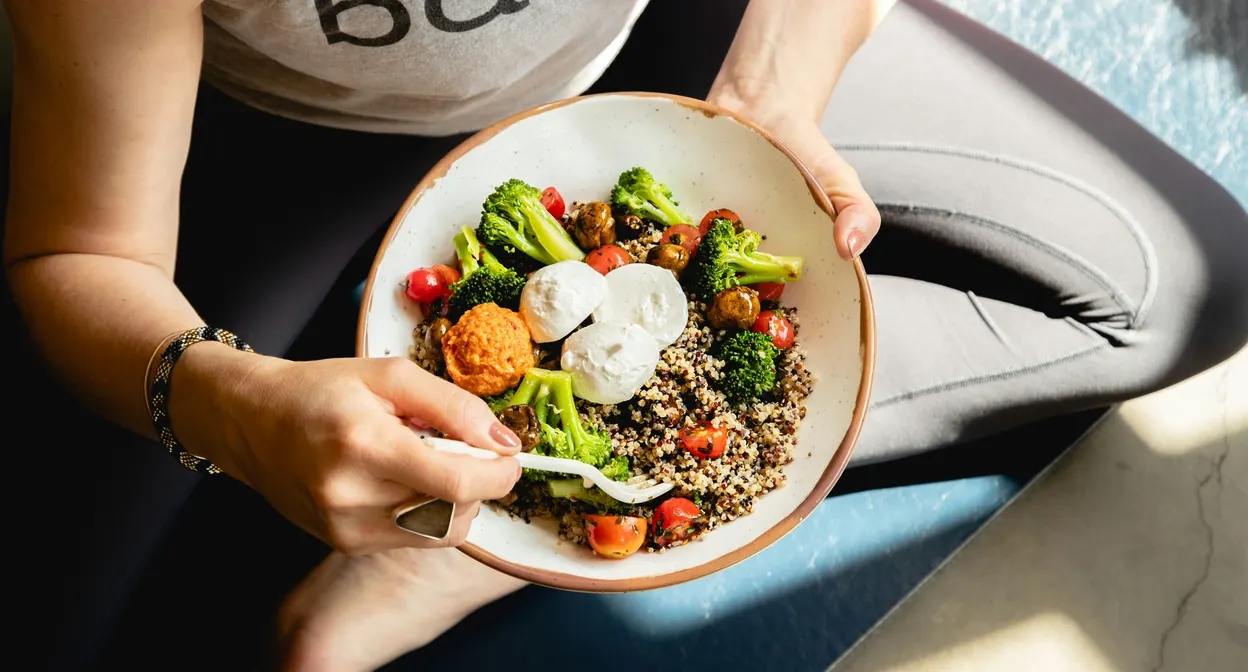 Un bol de quinoa, brocolis et burrata tenu à deux mains