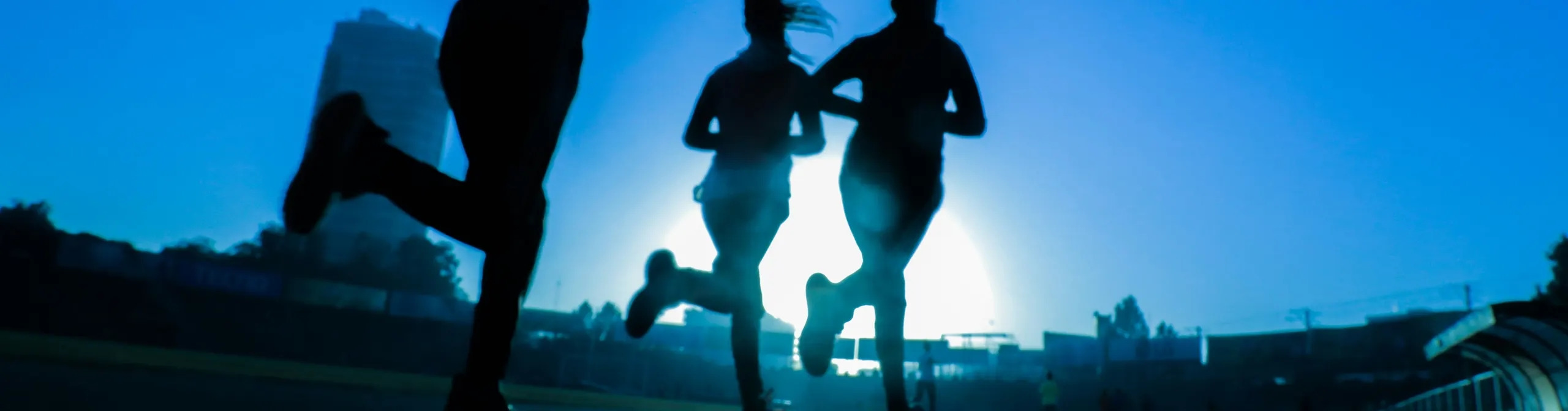 Trois coureurs en contre-jour sur une route au crépuscule