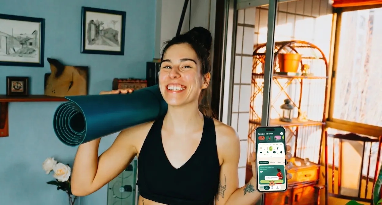 Une adhérente Bubble Boost, tapis de yoga sur l’épaule et application à la main